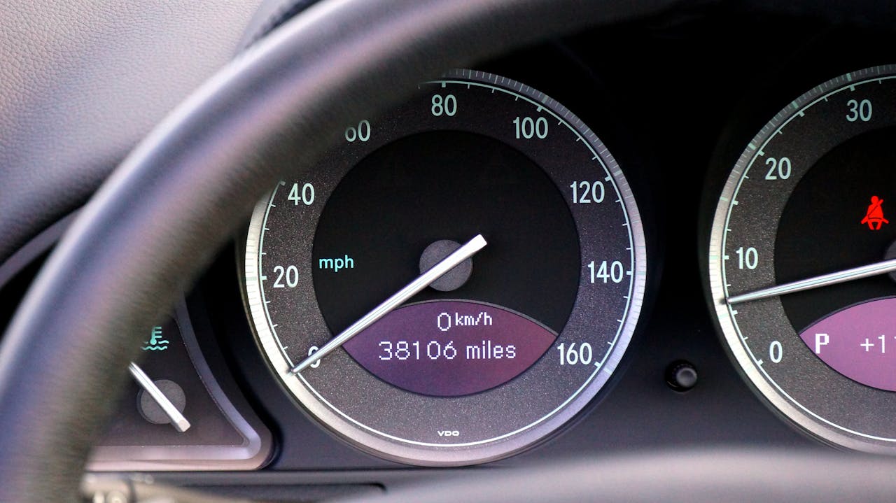 why-choose-us Close-up view of a car speedometer and mileage display with steering wheel in view.
