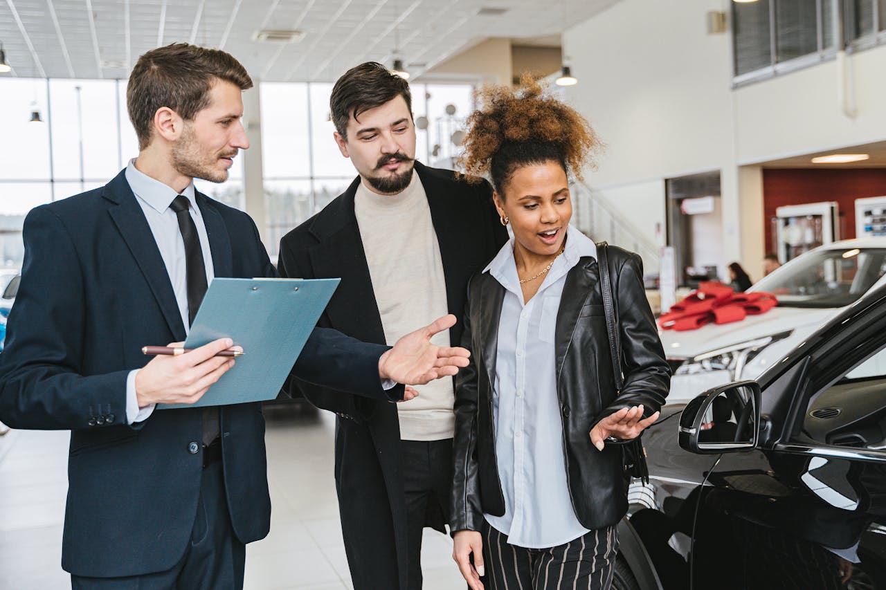 who-we-are A diverse group of adults discussing vehicles at a bright modern car dealership.