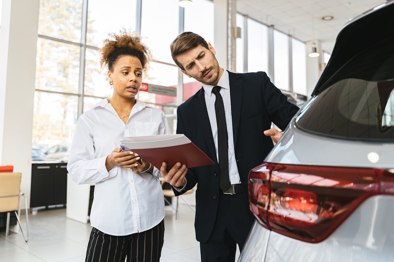 services-03 A professional consultation at a car dealership involving a sales agent and a customer discussing a vehicle purchase.